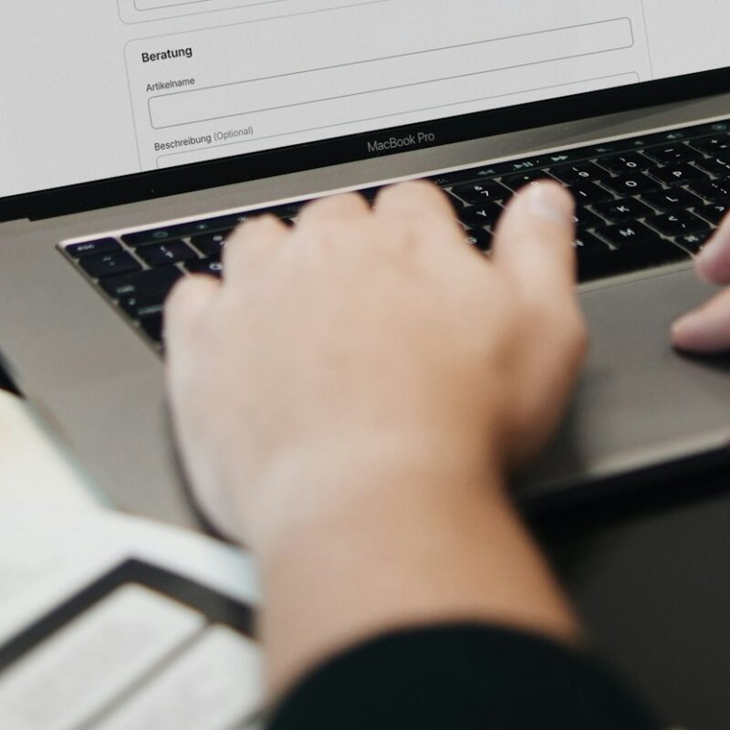 Hände auf einer Laptop-Tastatur mit Geschäftsunterlagen – E-Invoicing in den VAE und Saudi-Arabien